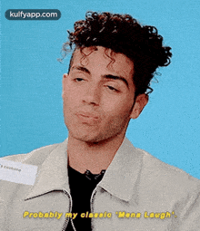a man with curly hair is making a funny face and saying probably my classic mena laugh .