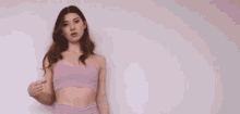 a woman in a purple top and pants is standing in front of a white wall .