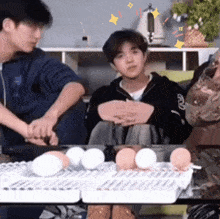 a group of people are sitting around a table with eggs on it and one of them has the letter r on his sleeve