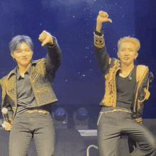 a couple of men standing on a stage with their arms up