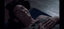 a shirtless man is laying on a bed with his eyes closed and smiling .
