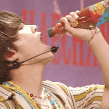 a man wearing a microphone drinks from a bottle that says ' cherry ' on it