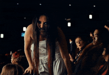 a woman with long white nails is sitting in a crowd