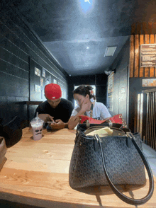 a man in a red hat sits at a table with a woman in a white shirt