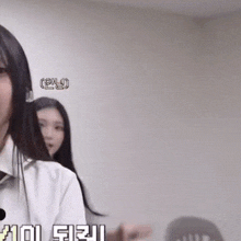 a woman in a white shirt and tie is standing in front of a wall with a foreign language written on it
