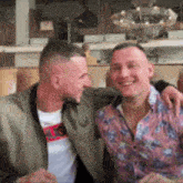 two men are sitting next to each other and smiling .