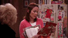 a woman in a pink sweater holds a christmas card