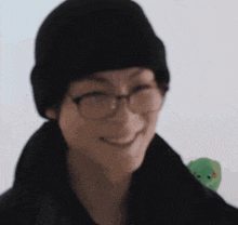 a close up of a person wearing glasses and a black hat .