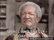 an older man with a beard is making a funny face and saying `` small and smelly dayumm '' .