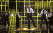 a group of men in suits and ties are dancing on a stage in front of a clock