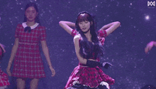 a group of women are dancing on a stage in front of purple lights