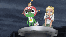 a girl stands next to a green frog with a star on his head