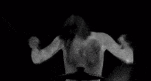a black and white photo of a shirtless man playing a drum