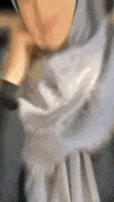 a blurry picture of a woman wearing a hijab and a gray dress .