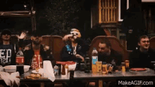 a group of people sitting at a table with a man wearing a shirt that says ed 32 on it