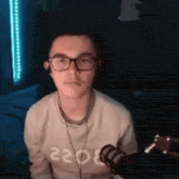 a man wearing glasses and headphones is sitting in front of a microphone in a dark room .
