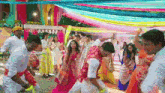 a group of people are dancing under a colorful canopy at a wedding reception .
