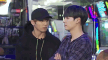 two young men are standing next to each other in an arcade and talking .