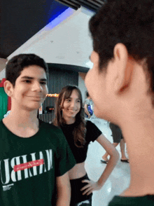 a boy wearing a green t-shirt with the letter j on it is standing next to a girl