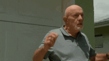 a bald man with a beard is holding his head in his hands