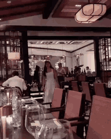 a woman in a white dress walks into a restaurant