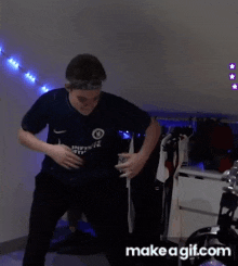 a man in a nike shirt is dancing in a room