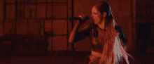 a woman singing into a microphone with her hair blowing in the wind