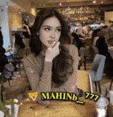 a woman sits at a table with mahnb_777 written on the table