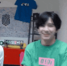a young man wearing a green shirt with the number 0 on it is smiling .