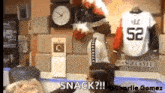 a man in a white shirt with the number 52 on it is standing in front of a clock and a sign that says snack .