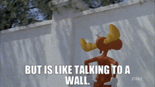 a cartoon character with horns is standing next to a white fence and talking to a wall .
