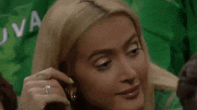 a close up of a woman adjusting her earring while wearing a ring .