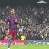 a soccer player is running on the field in front of a crowd sponsored by laliga