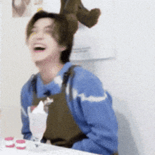 a man wearing an apron and a blue sweater is laughing