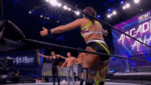 a woman is standing in a wrestling ring with a group of men