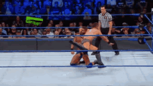 two men are wrestling in a wrestling ring while a referee looks on .