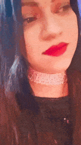 a close up of a woman wearing a choker and red lipstick .