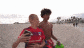 two young boys are walking on a beach one is wearing a shirt that says childrens health