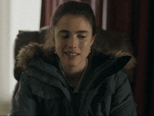 a woman wearing a grey parka with a fur hood