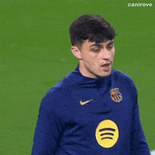 a soccer player wearing a blue nike jersey holds his hand to his forehead .