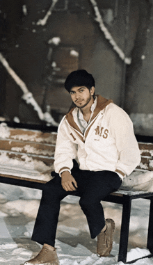 a young man wearing a white jacket with the letter ms on it