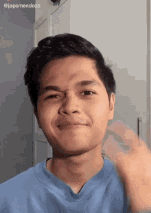 a young man in a blue shirt is making a face