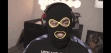 a man wearing headphones and a black mask with a yellow infinity symbol on his face