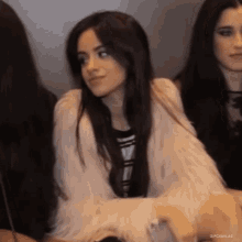 a woman in a fur coat is sitting next to two other women .
