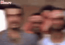 a blurry picture of three men standing next to each other with their faces visible .