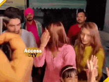 a group of people are standing next to each other in a room . one of the women is wearing a pink shirt .
