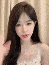 a woman with long black hair is wearing a white tank top and necklace .