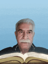 a man with a mustache is reading a book with a blue background