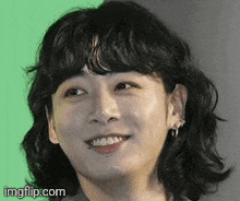 a close up of a person 's face with curly hair smiling .