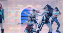 a group of women are dancing in a room with a colorful background .
